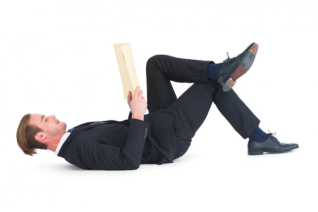 Relaxed businessman lying and reading book