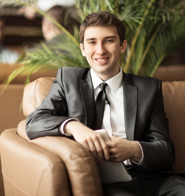 Relaxed businessman sitting in front of the windows of the office