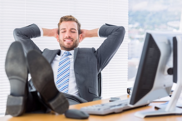 Photo relaxed businessman sitting with legs on desk