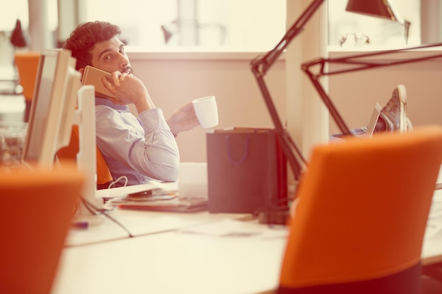 Foto uomo d'affari rilassato sul posto di lavoro al mattino presto in un momento di relax presso l'ufficio di avvio