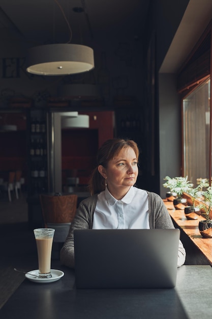 relaxed businesswoman working remotely on her laptop computer contemplate managing her work