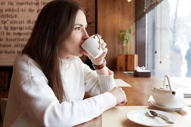 リラックスした白人女性がお茶やコーヒーを飲む