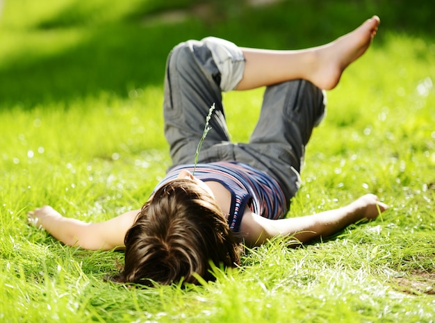 リラックスした子供、夏の公園の草原に休息