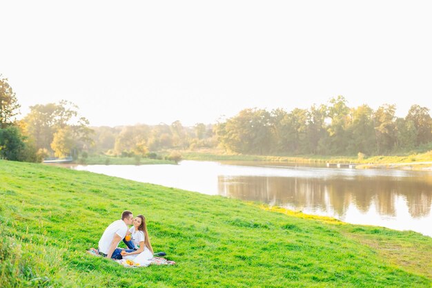 湖の近くでピクニックをしているリラックスしたカップルは、公園でロマンチックなデートをし、若者たちは話している