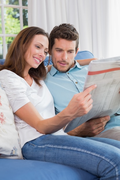 Relaxed couple reading newspaper on couch