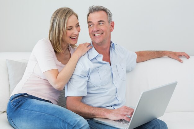 Relaxed couple using laptop at home