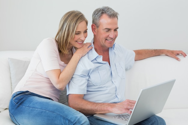 Relaxed couple using laptop on sofa