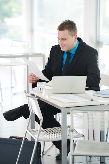 Relaxed executive sitting on desk in office