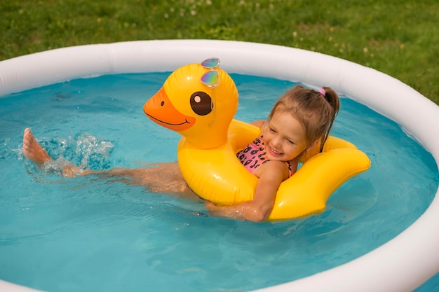 편안 한 소녀 는 뒷마당 에 있는 작은 수영장 에서 물 표면 에 있는 원 으로 수영 하고 있다