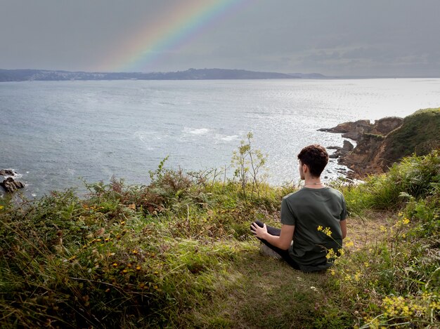 Relaxed guy sitting on the grass meditating