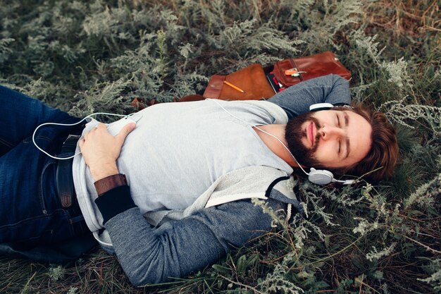 Relaxed guy sleeping outdoor in headphones.