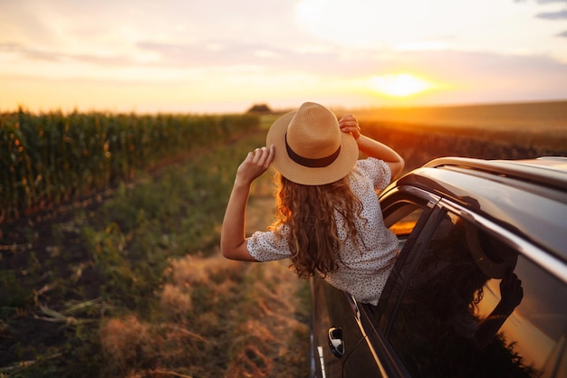 車の窓から身を乗り出す夏のロードトリップ旅行休暇でリラックスした幸せな女性