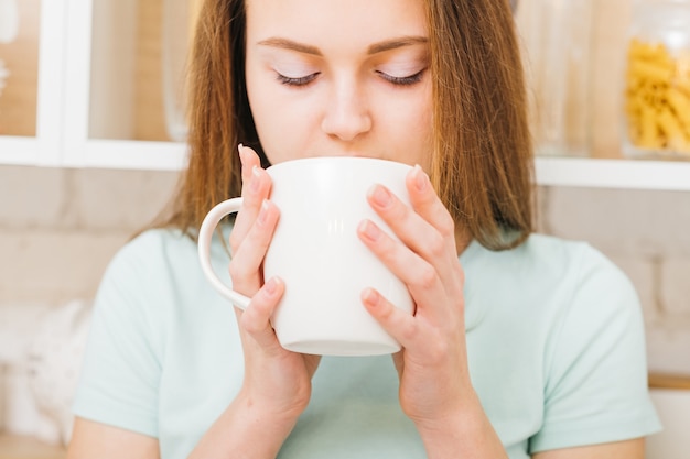 Relaxed home leisure. Morning tradition. Woman enjoying a cup of hot beverage in white cup