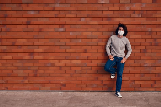 Relaxed man in mask leaning on wall