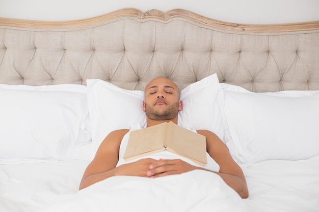 Relaxed man with book lying in bed