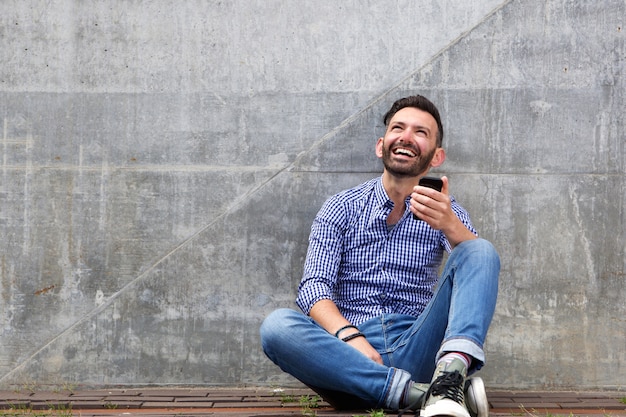 Relaxed middle aged man sitting against a wall 