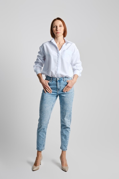 Фото Расслабленная женщина средних лет в белой рубашке и синих джинсах