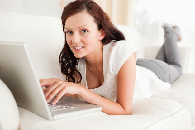 Relaxed redhaired woman searching the internet looking into the camera