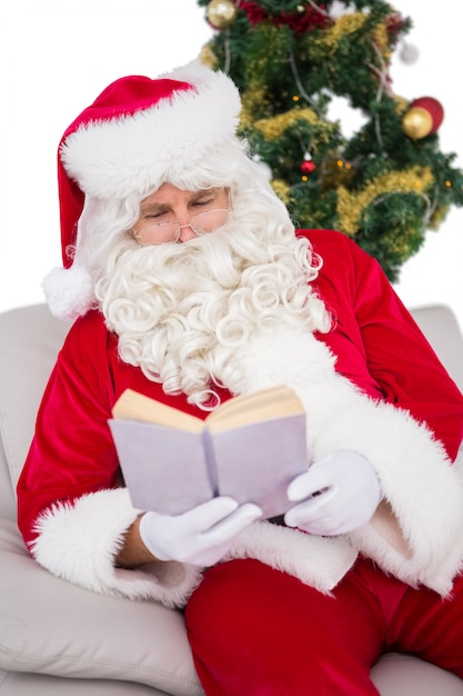 Relaxed santa reading on the couch