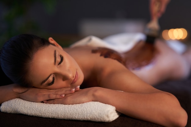 Relaxed smiling woman receiving a chocolate back massage in a spa