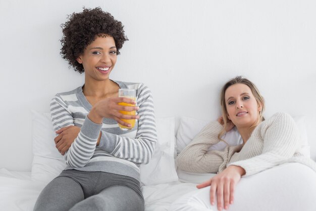 Relaxed smiling young female friends in bed