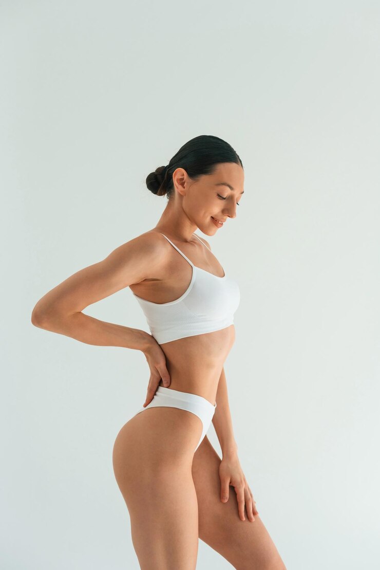 Photo relaxed standing against white background young woman with slim body type is in fitness clothes in the studio
