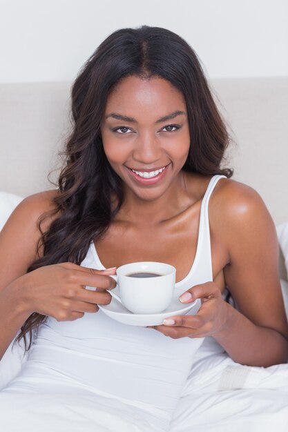 ベッドでコーヒーを飲むリラックスした女性