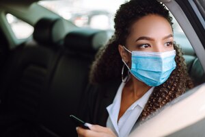 Foto relaxed woman passenger in protective medical mask in the taxi car