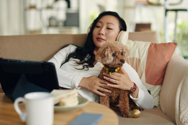 Фото Расслабленная женщина ласкает маленькую собачку.