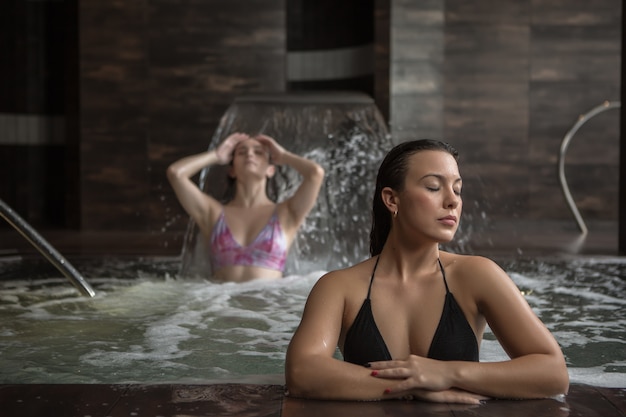 Relaxed woman resting in spa pool with girlfriend