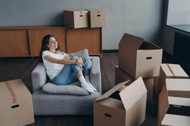 Relaxed woman rests in armchair during packing things for moving at new home Mortgage advertising