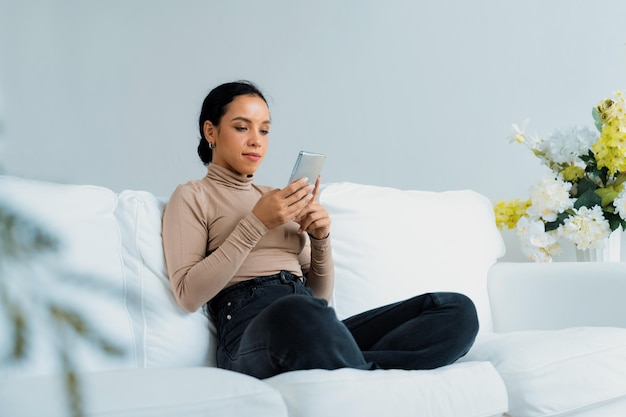 Photo relaxed young african american woman using crucial mobile phone on sofa couch in living room at home