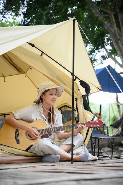 기타를 연주하는 편안한 젊은 아시아 여성 여행자 야외 여름 활동 개념