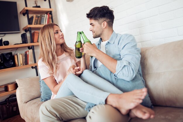 Relaxed young couple drinking beer in living room