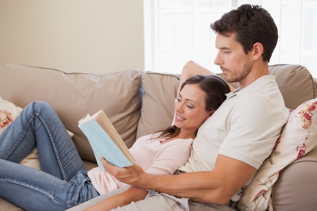 Relaxed young couple reading book on couch