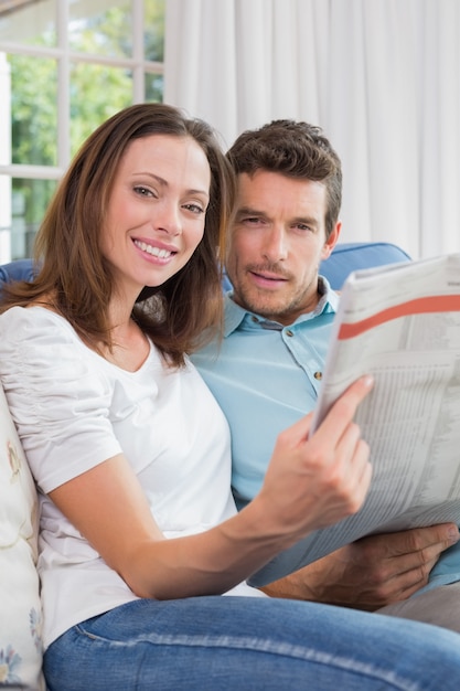 Relaxed young couple reading newspaper on couch