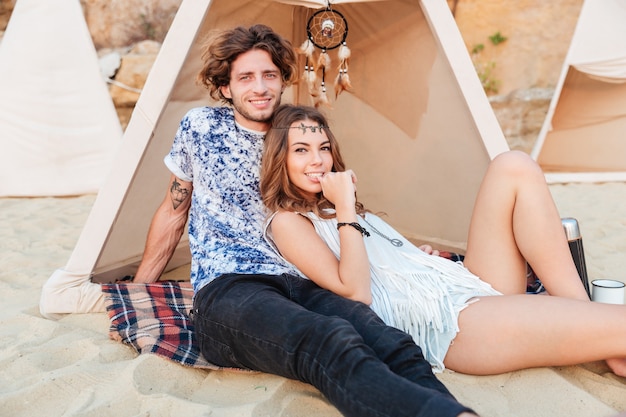 Relaxed young couple sitting in wigwam on the beach