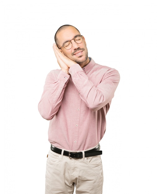 Relaxed young man making a gesture of sleep