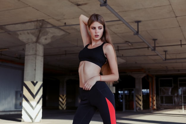 Relaxed young sportswoman standing outdoors and smiling. Slim female athlete after workout in morning.