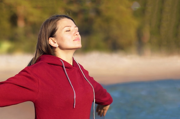 Relaxed young woman breathes fresh air in nature on the beach