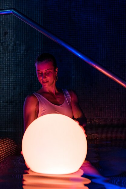 Relaxed young woman in pool with neon light