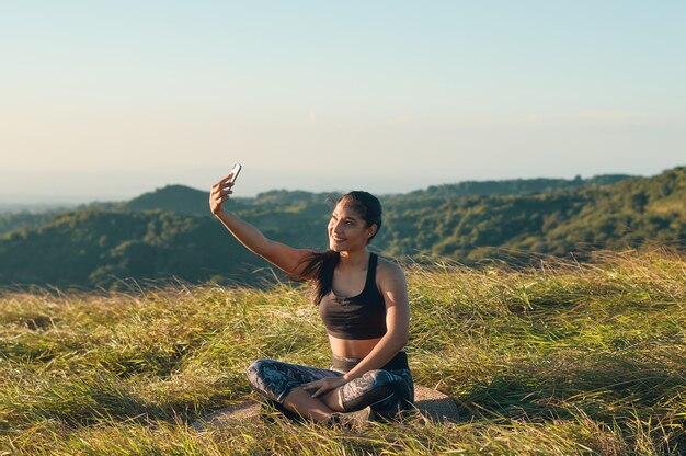 屋外で運動した後、スマートフォンで自分撮りをしているリラックスした若い女性