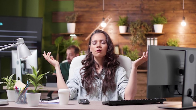 Photo relaxed zen businesswoman with closed eyes standing in yoga position meditating during work pause in startup business company office. entrepreneur worker concentrating on breathing