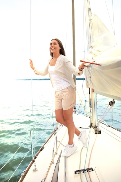 Relaxing attractive young woman on vacation standing on yacht.