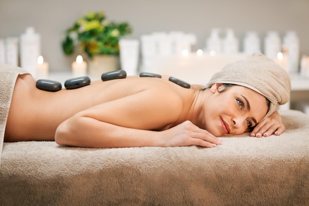 Relaxing female during hot stone massage in spa