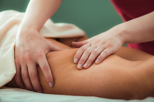 Relaxing legs massage hands of a female massage therapist massaging female client's legs