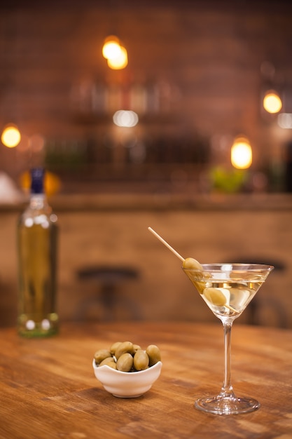 Relaxing in a pub with a glass of dry martini on a wooden table. Fresh drink. Tasty drink.