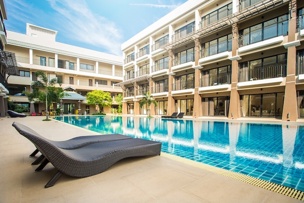 Relaxing rattan chairs with pillows beside swimming pool