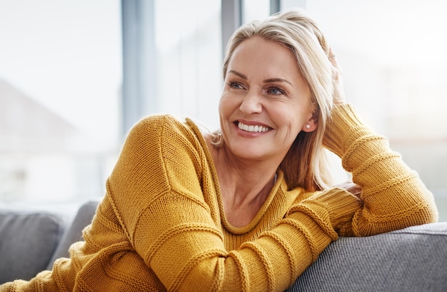 Photo relaxing really lifts the spirits shot of an attractive mature woman relaxing on the sofa at home