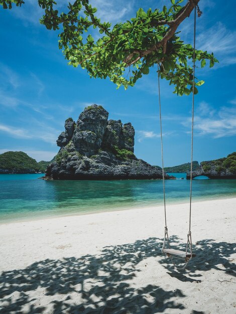 Photo relaxing swing on white sand beach of stunning rock formation island mu koh ang thong thailand